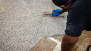 Worker applying JetRock Epoxy flooring over commercial quarry tile.