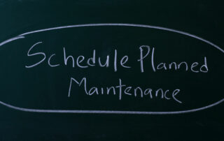 the words schedule planned maintenance written on a chalkboard